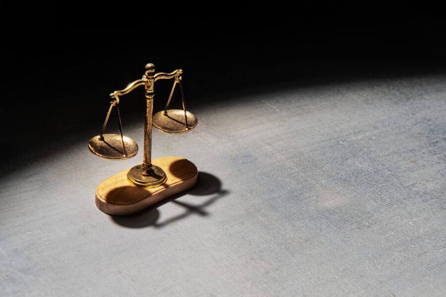 A,Scale,Of,Justice,Illuminated,By,A,Spotlight,Stands,Against